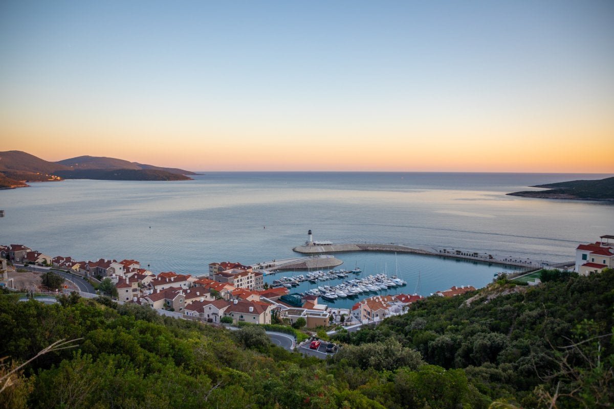 Seaside marina with boats and a small coastal village at sunset, overlooking the calm sea and scenic.