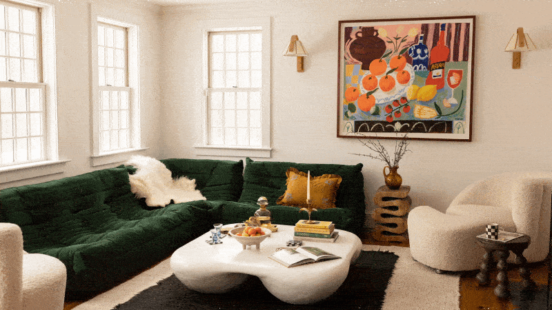 Bright living room with dark green sofa, white curvy coffee table, art on wall, and beige chairs.
