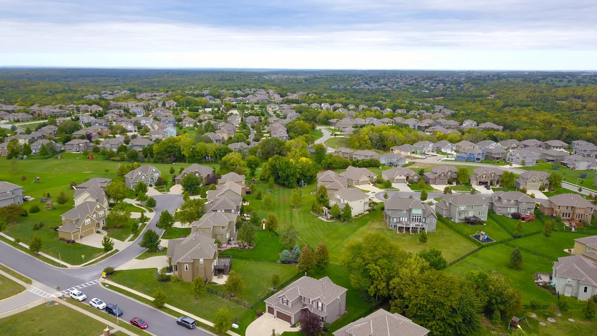 Aerial view of homes, streets, and green spaces in a residential neighborhood.