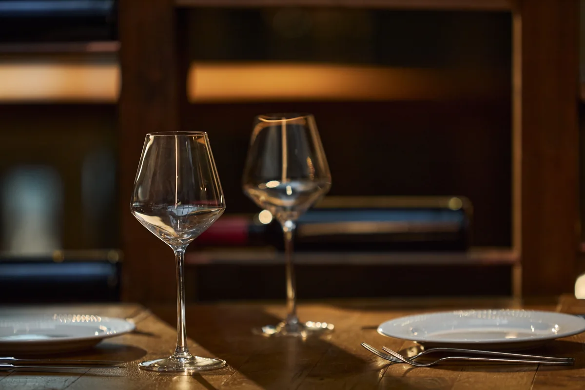 Empty wine glasses and plates set on a restaurant table