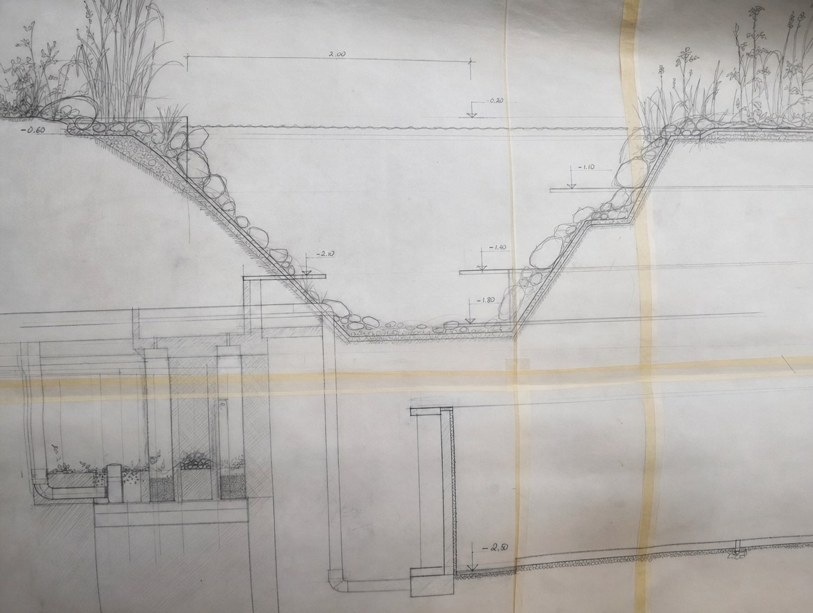 Pool design plans and drawings spread out on a garden table with a tape measure