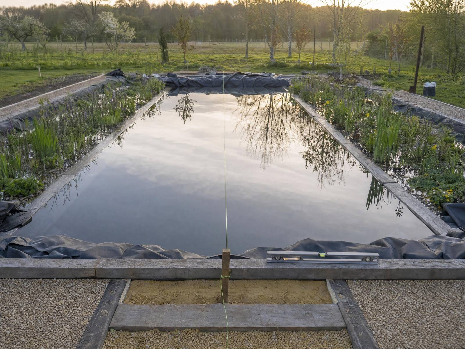 Natural pool under construction, showing the excavated chamber, timber formwork and a digger