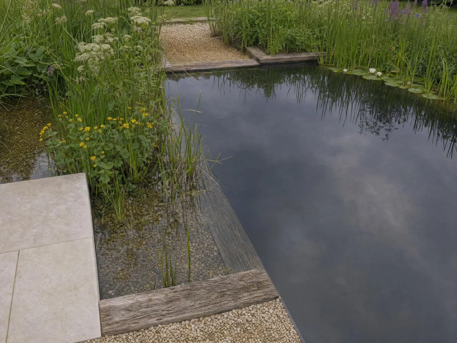 Natural pool set in lawn beside a brick manor house