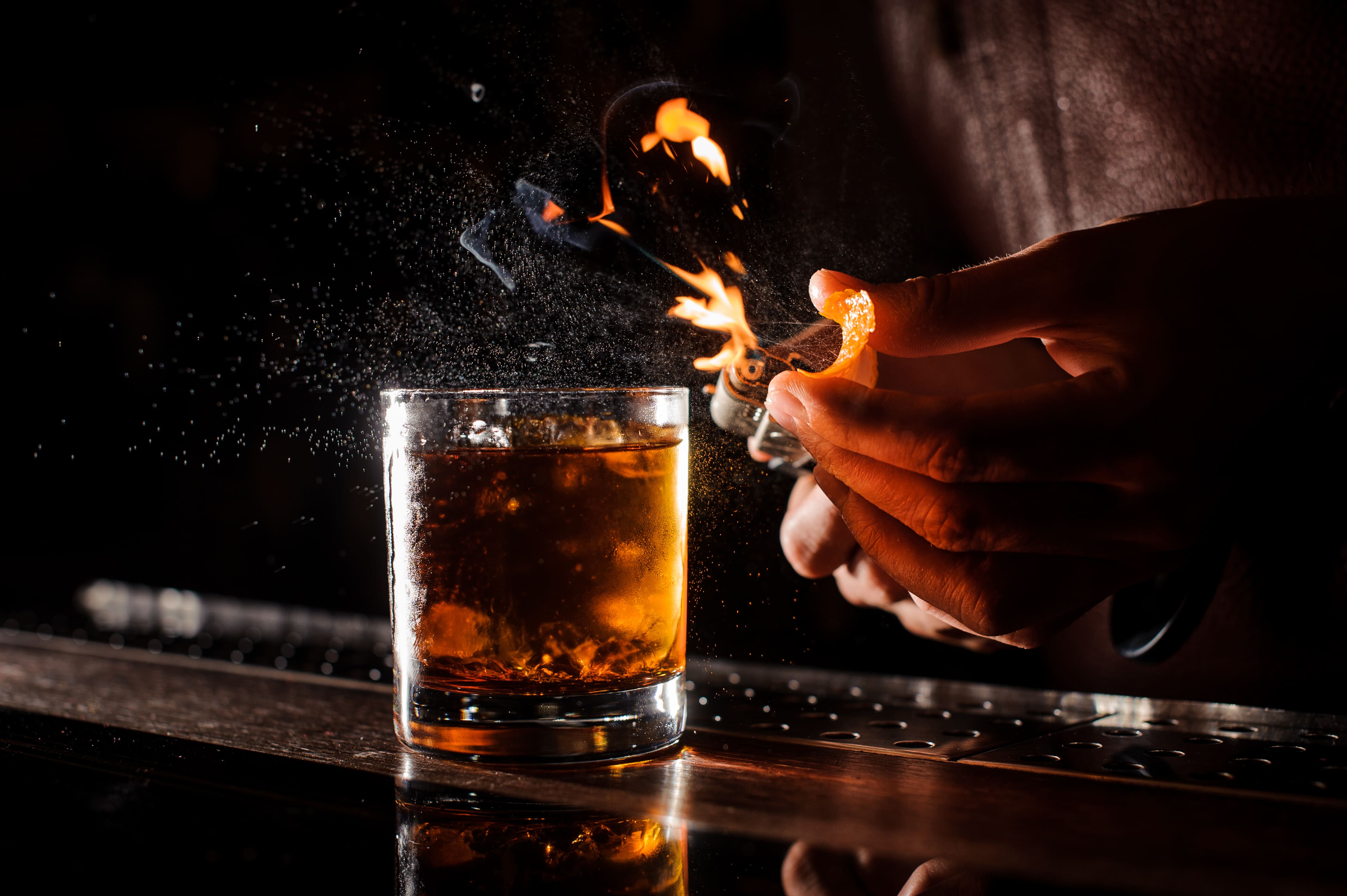 Bartender flaming an orange peel over a chilled cocktail Absolut Sprite