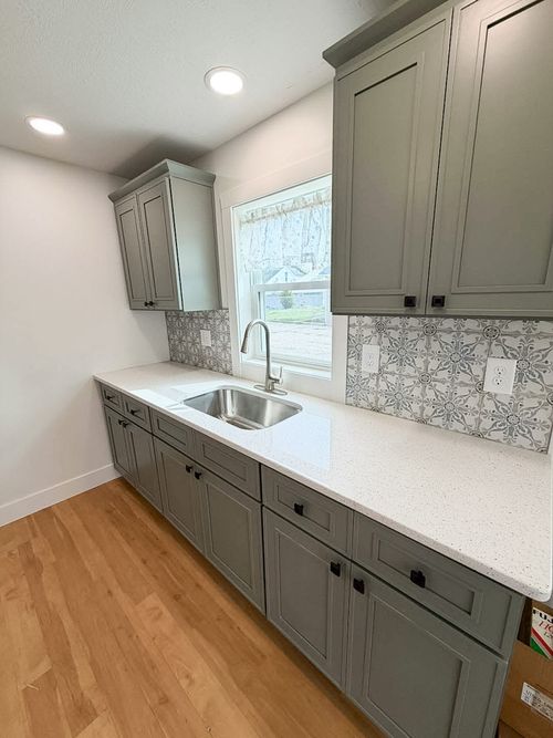 New home build with updated kitchen sink and plumbing with white counter top and green cabinets