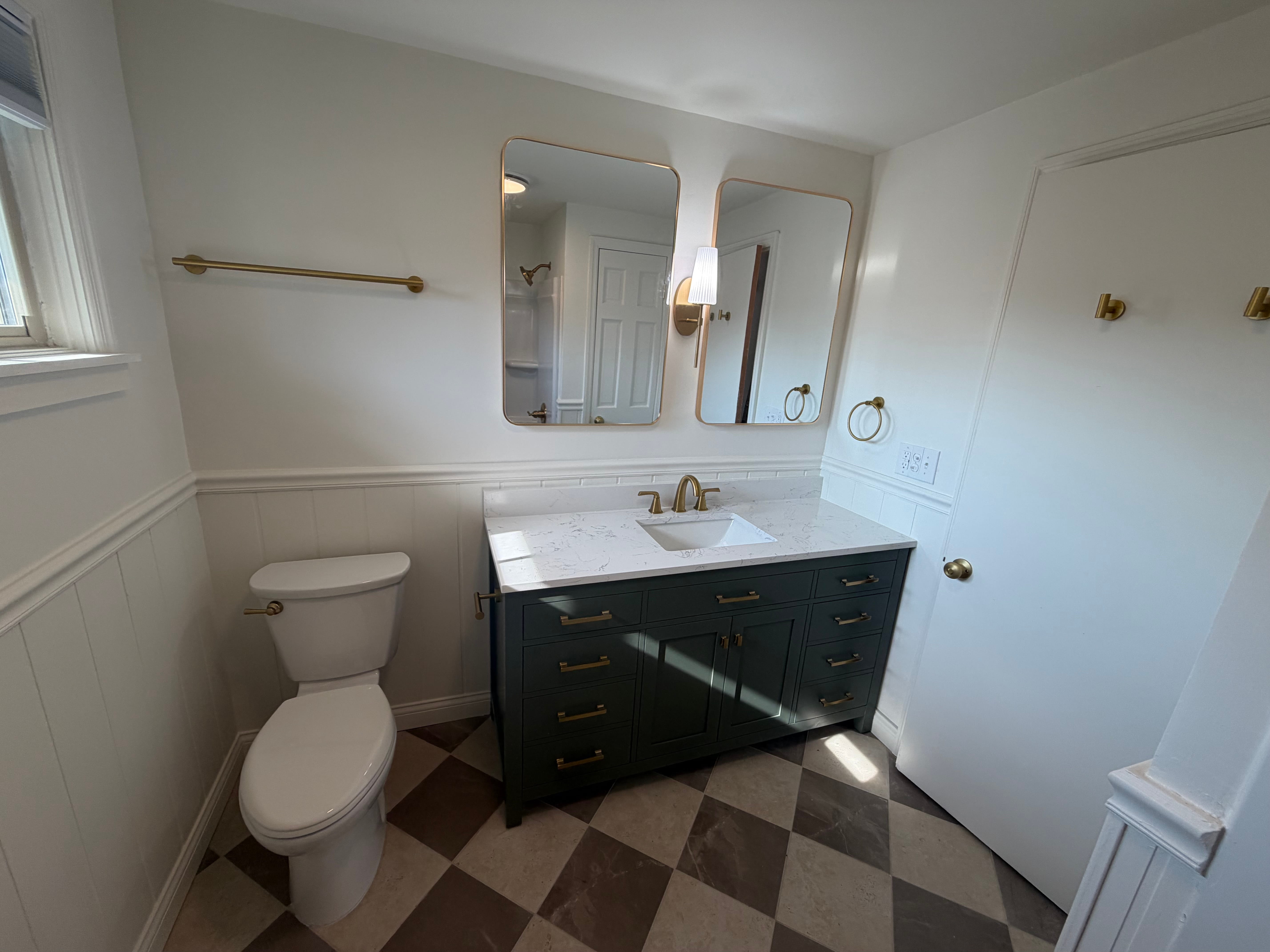 Updated dark blue bathroom vanity and fixtures with tan and brown flooring