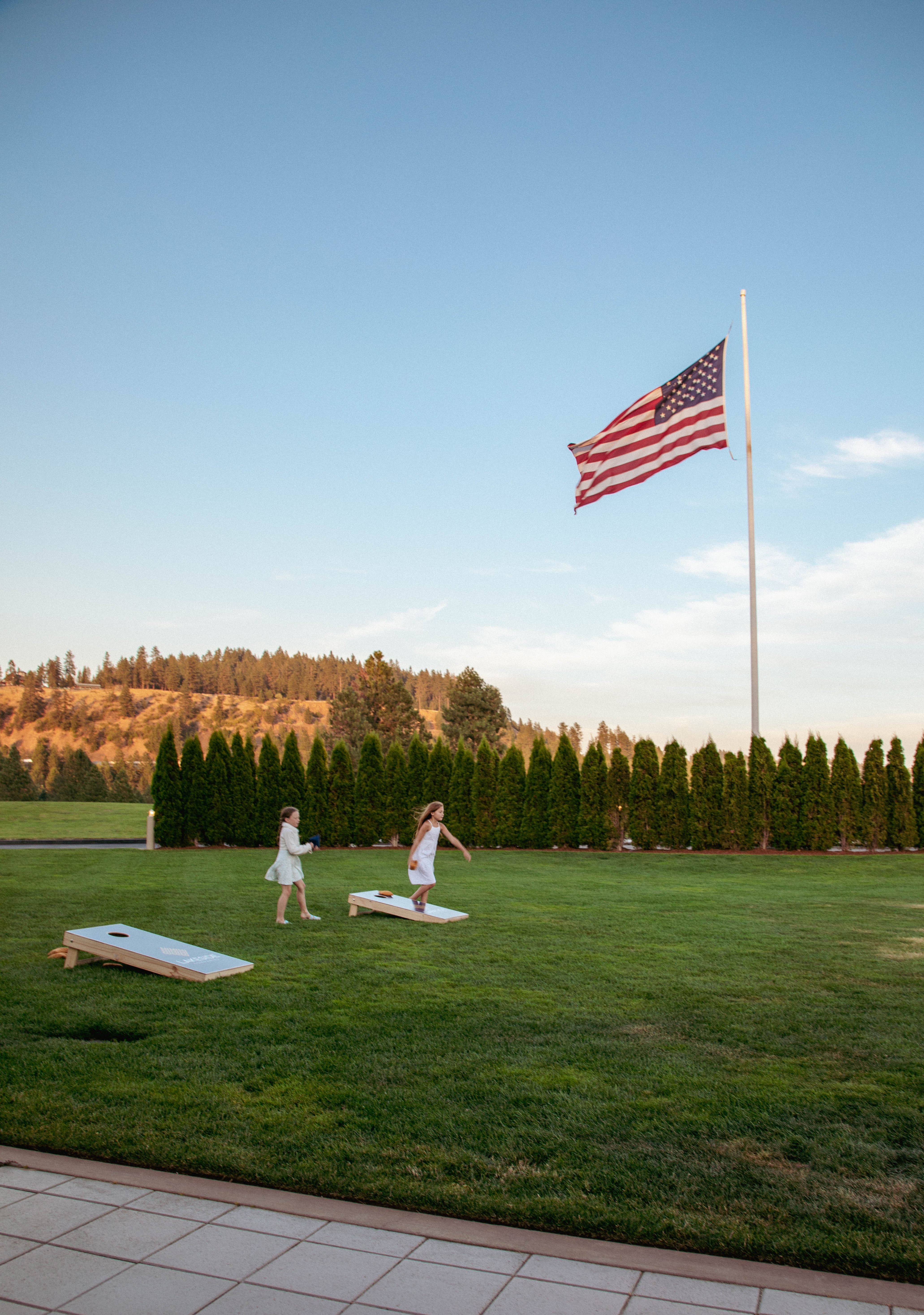 Children playing on a lawn beneath an American flag