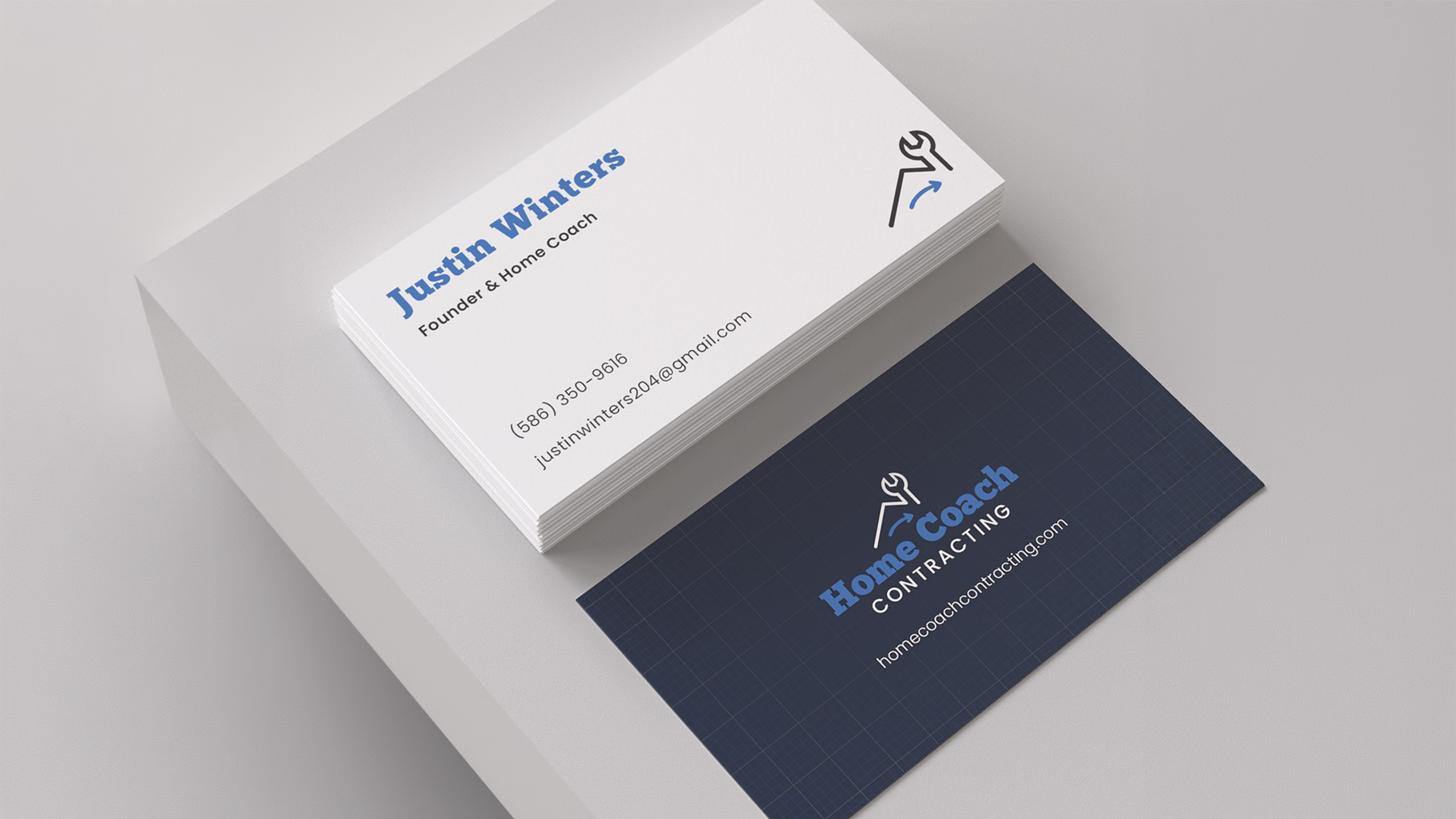Mockup of Home Coach Contracting business cards, front and back, on a navy blueprint-style design