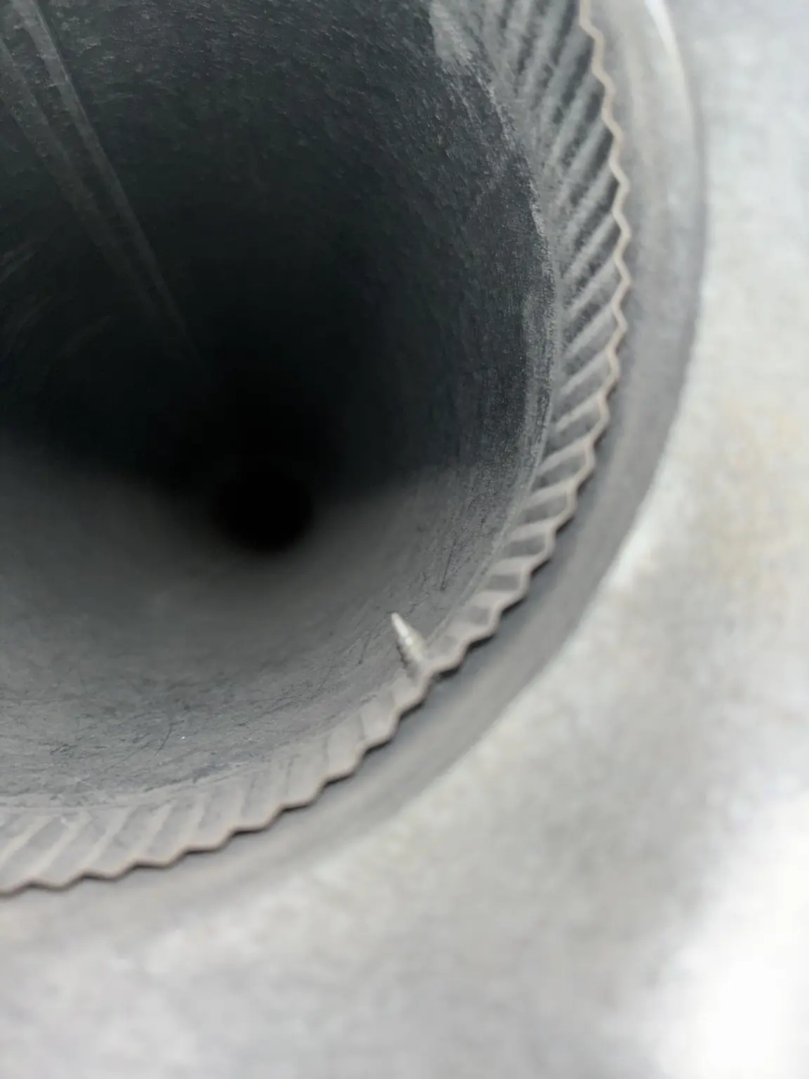 Clean round metal air duct interior with visible seam and screw.