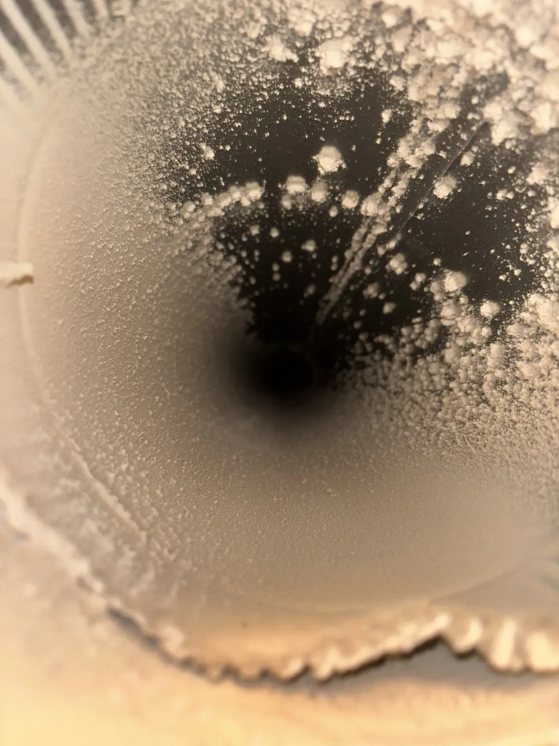 Inside view of a round duct with dust buildup forming speckled patterns on its surface.