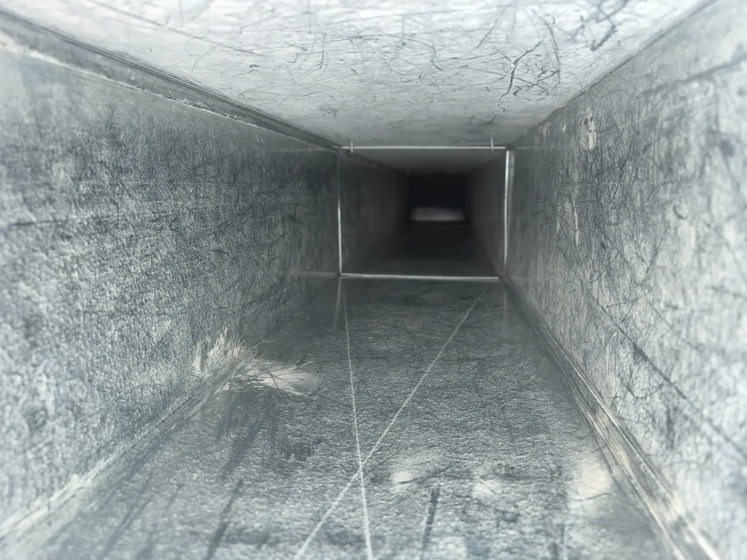 Interior view of a clean, empty rectangular metal air duct with smooth surfaces.