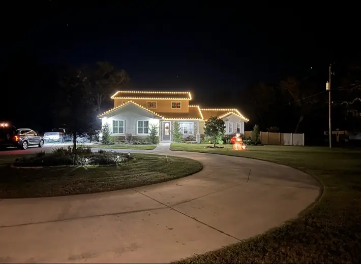 Large home with professionally installed warm white roofline holiday lights