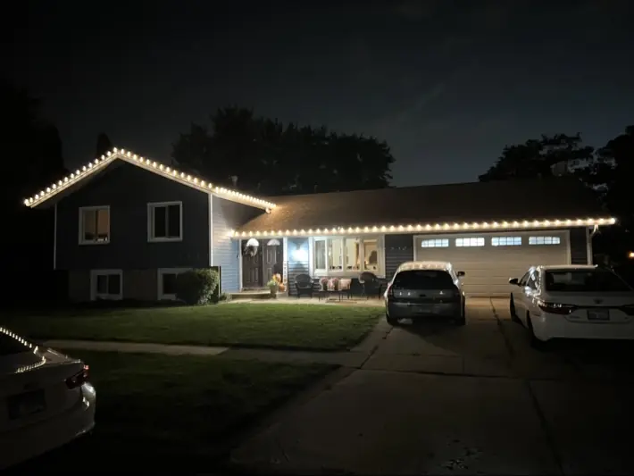 Split-level home with warm white roofline holiday lights