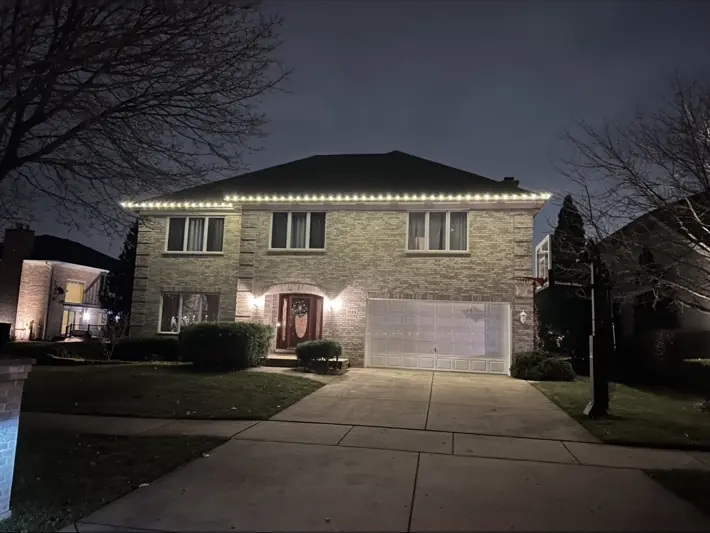 Two-story home with warm white roofline holiday lighting