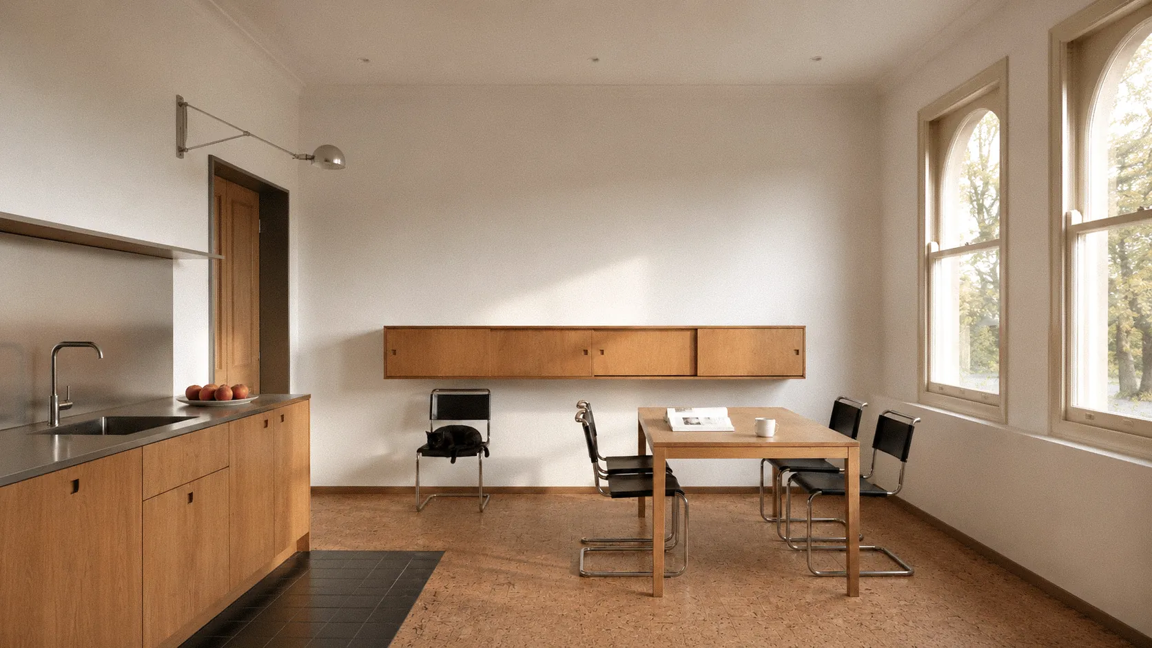 Minimalist kitchen with wooden cabinets, a dining table with black chairs, and a cat on a chair.