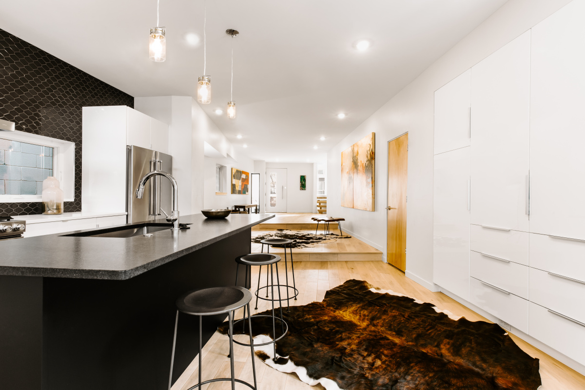Kitchen with black island, white cabinetry and scale-pattern tile backsplash
