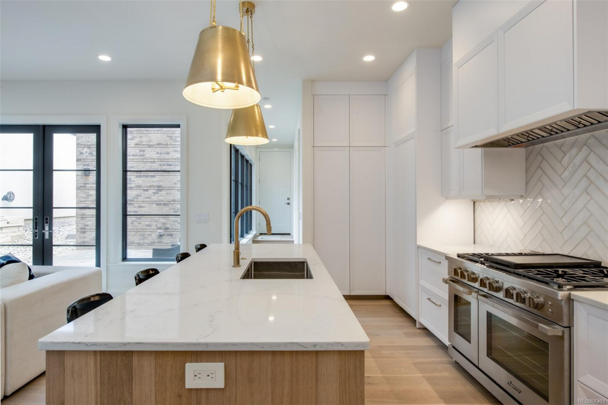 Kitchen with white oak island, marble counters and brass pendant lights