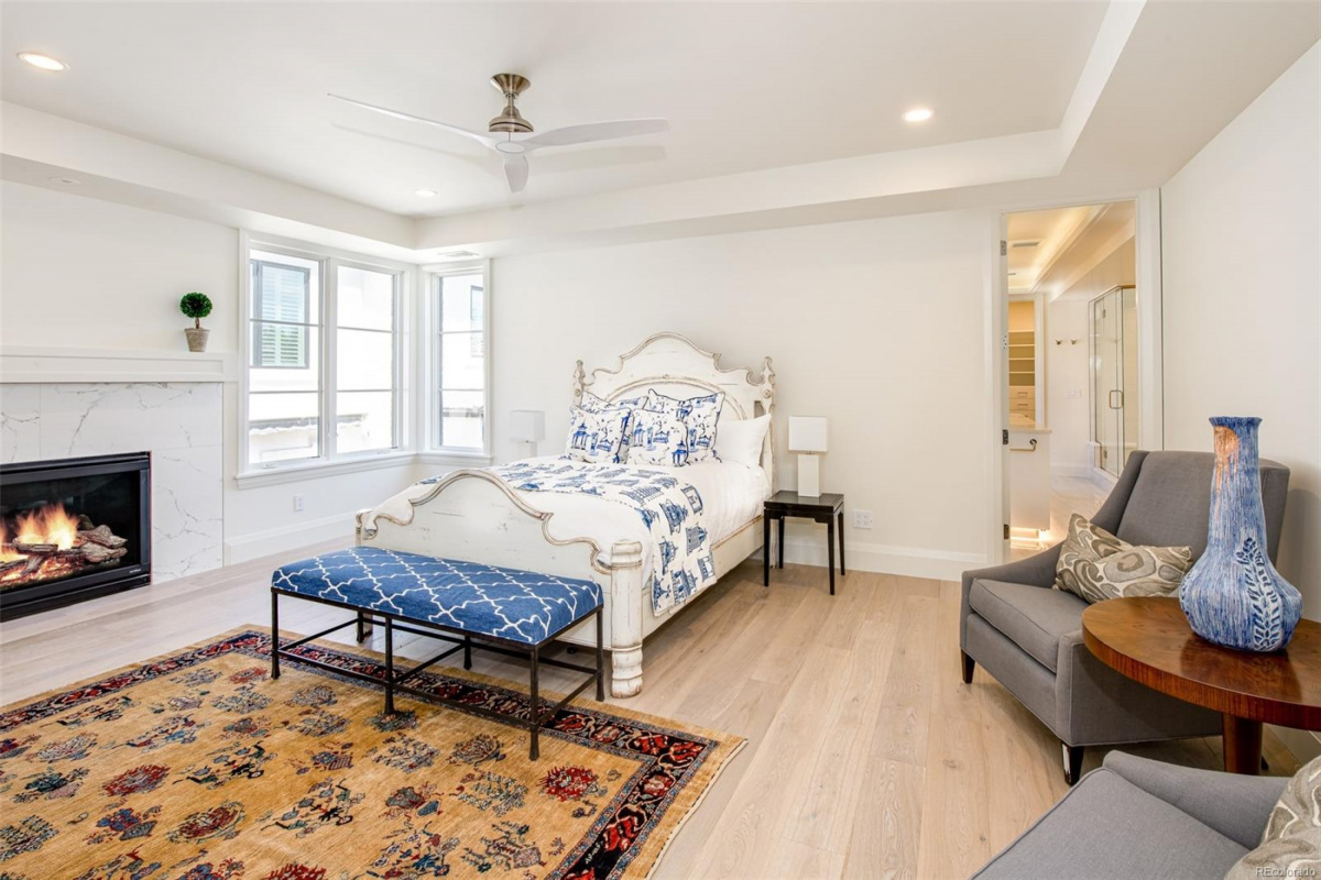 Primary bedroom with marble fireplace, tray ceiling and sitting area