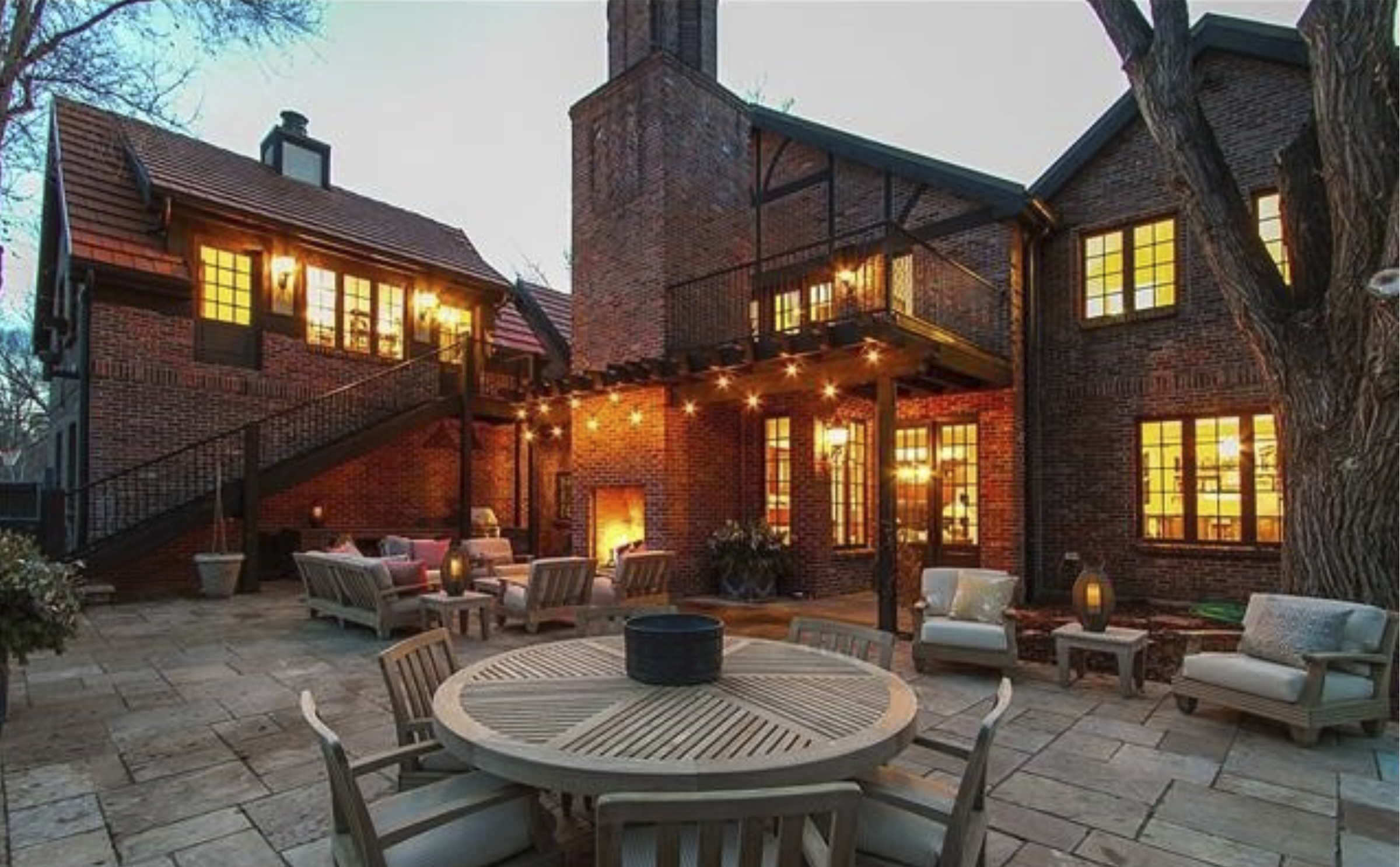 Flagstone terrace with outdoor fireplace, lounge seating and a round dining table