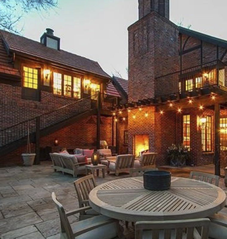 Brick courtyard with outdoor fireplace and patio dining under string lights