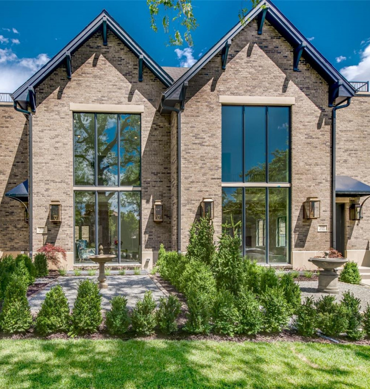 Twin-gable brick facade with tall steel windows and a landscaped courtyard