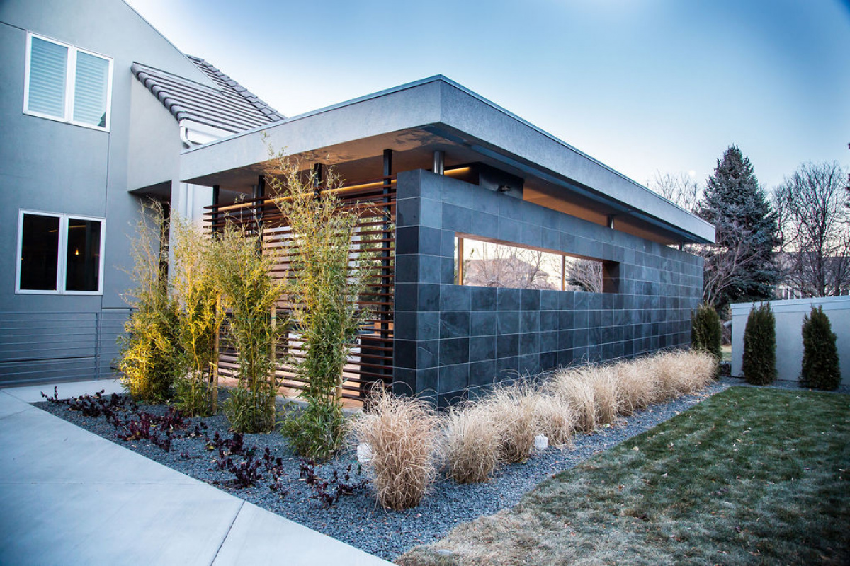 Slate-tiled outdoor living pavilion with slat privacy screen and ornamental grasses in Cherry Hills Village
