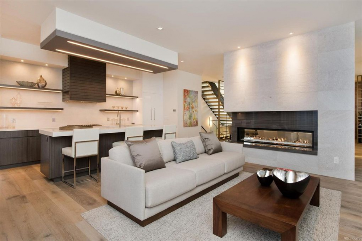 Living room with white sofa and linear fireplace open to the kitchen