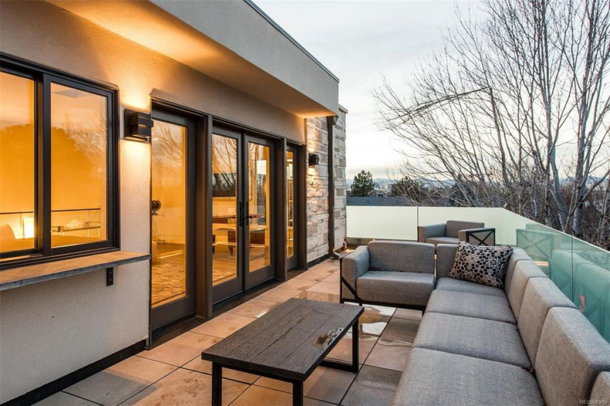 Rooftop terrace with gray sectional sofa and glass railing