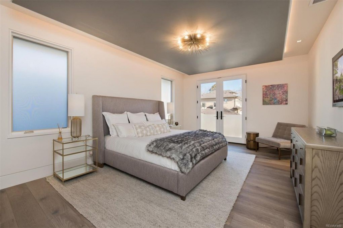 Primary bedroom with gray upholstered bed and French doors