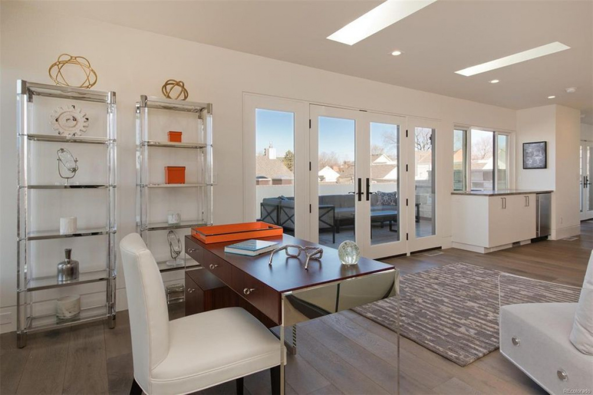 Home office with glass shelving and a desk beside tall windows
