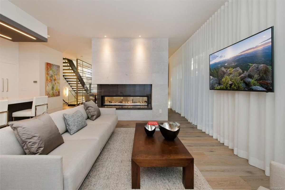 Living room with linear fireplace, wall-mounted TV and open staircase