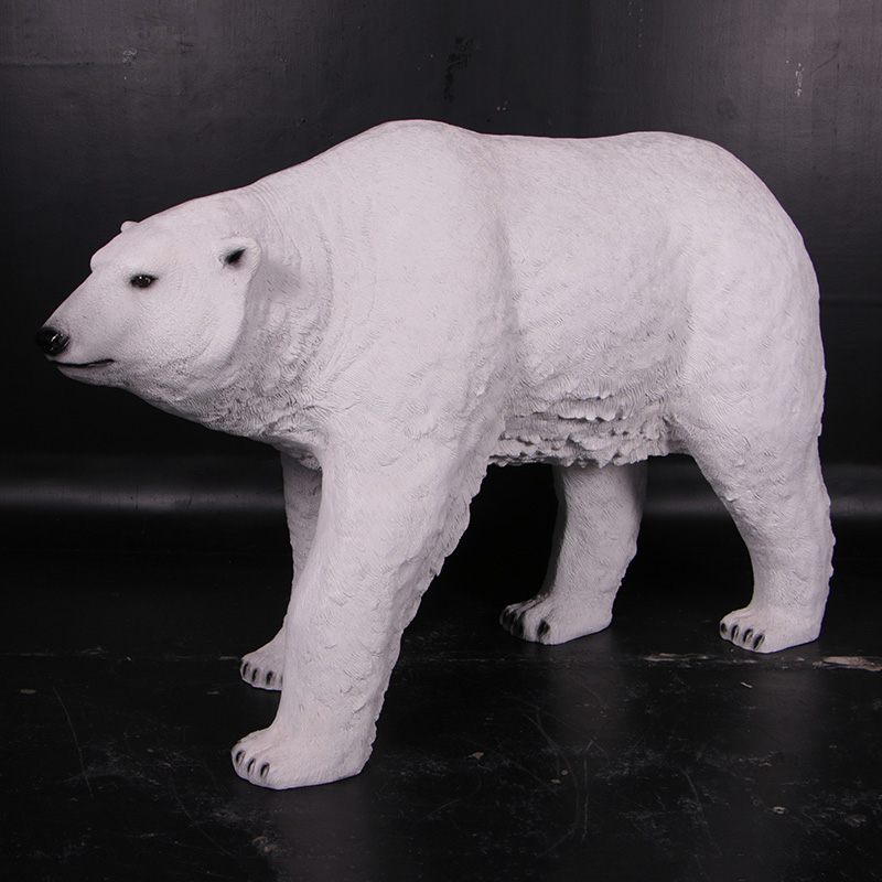 White polar bear sculpture standing on a black floor with a dark background.