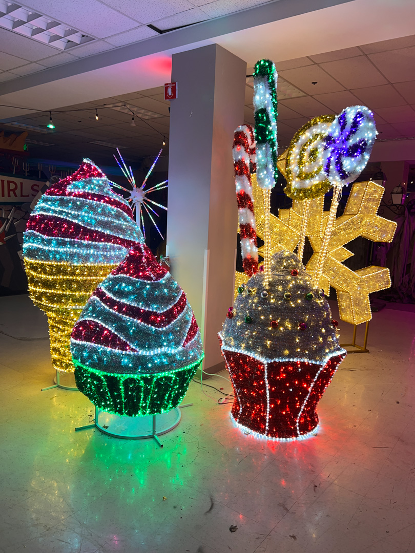 Indoor colorful holiday light decorations shaped like cupcakes, candy canes, lollipops, ice cream cone, and a snowflake.