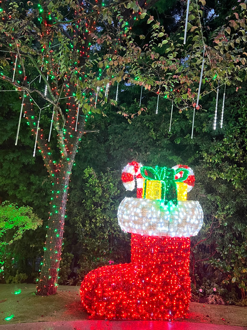 Large light up Christmas stocking decoration with lights and gifts outdoor.