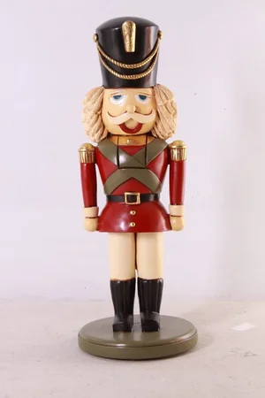 Decorative nutcracker soldier figurine wearing red and green uniform with a black hat.