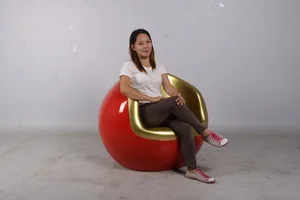 Woman sitting cross-legged on a red and gold ornament-shaped chair.