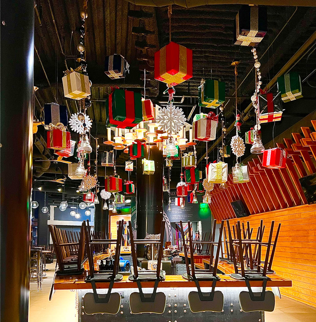 Interior venue decorated with hanging wrapped presents and snowflakes for Christmas season.