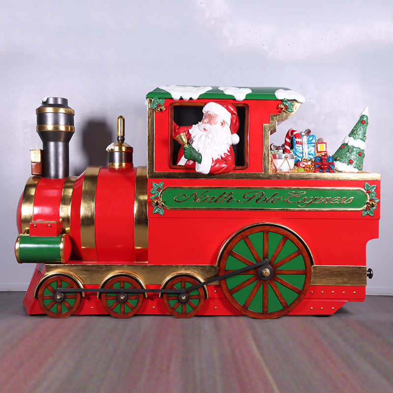 Decorative red and green North Pole Express train with Santa inside holding a bell with Christmas gifts behind him.