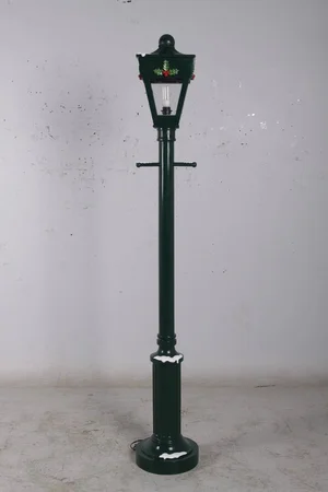 Tall black vintage streetlamp with snow accents on base and holiday decorations on lantern.
