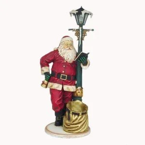 Santa Claus figurine leaning on a lamp post with a book and a sack at his feet.