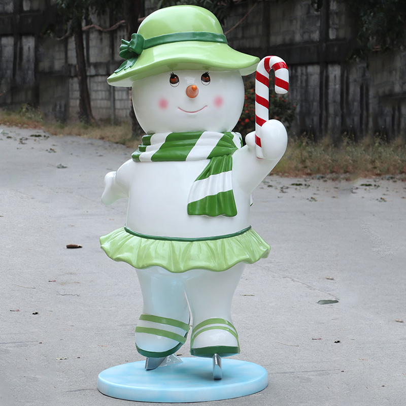 Smiling snowman figurine wearing green hat, scarf, skirt, ice skates, holding a candy cane.