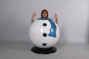 Person posing inside a snowman costume with head out, smiling with raised hands.
