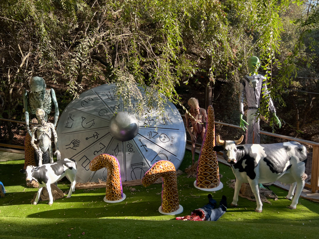 Outdoor Halloween display with alien, skeletons, cows, tentacles, and a large crashed UFO.