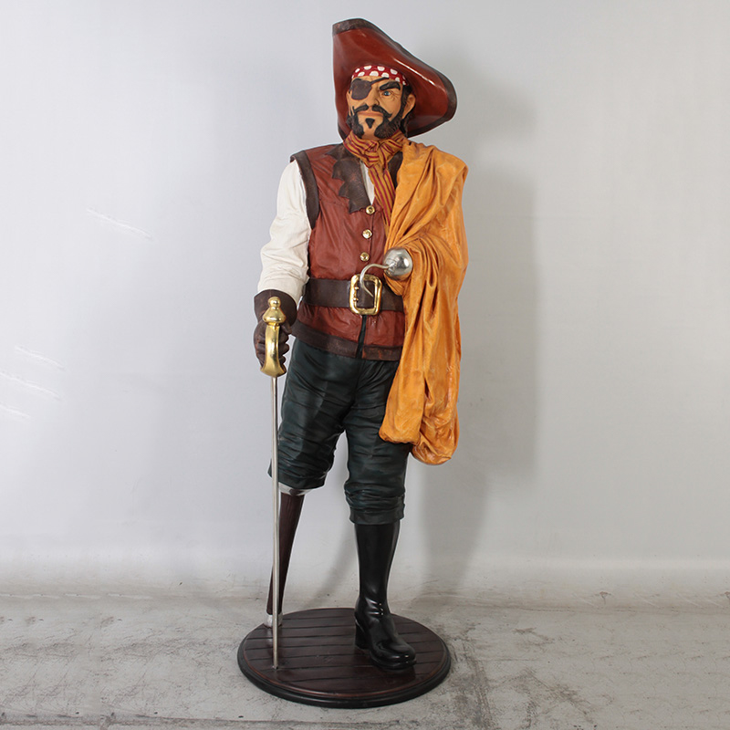 Statue of a pirate with an eye patch, red hat, striped bandana, holding a sword and orange cloth.