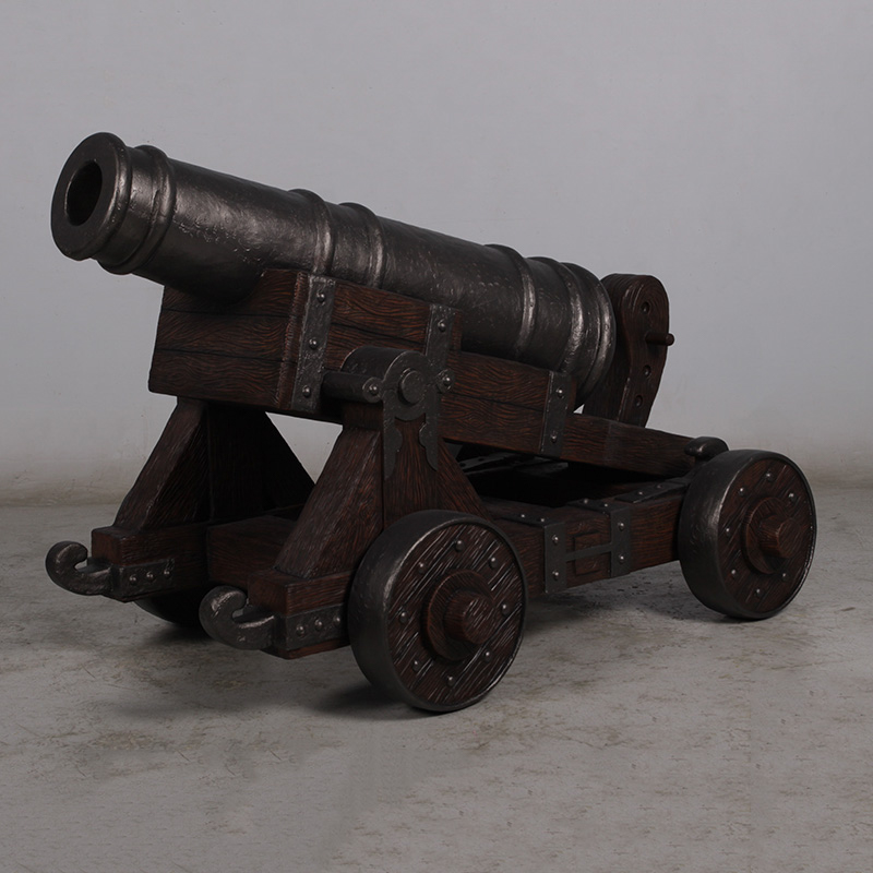 Antique black metal cannon mounted on a brown wooden carriage with large wheels on a concrete floor.