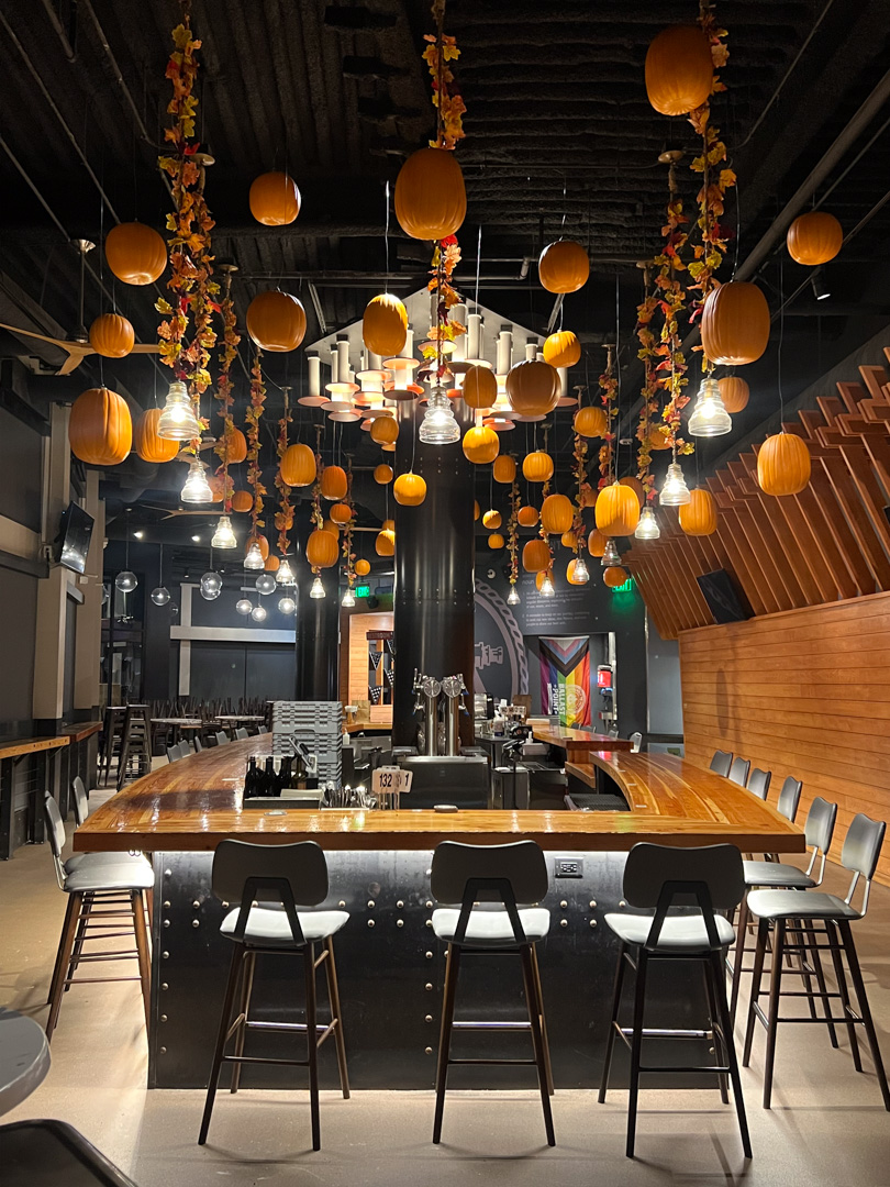 Dozens of pumpkins hang above a restaurant-style interior.