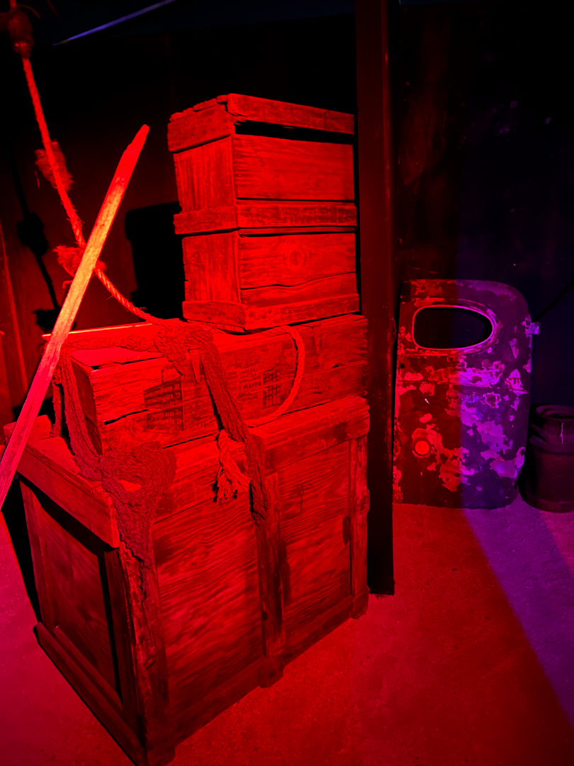 A rustic wooden structure and pumpkin props glow under red lighting.
