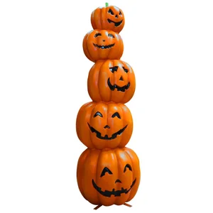 Stacked Halloween pumpkins of varying sizes with carved smiling faces, arranged as a tower.