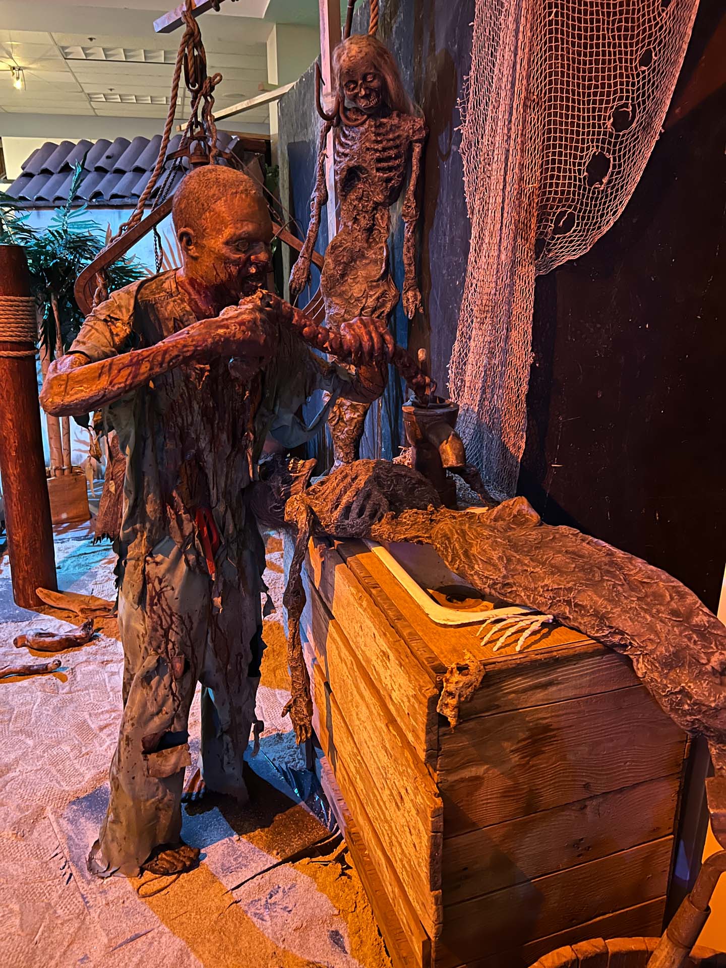 Zombie figure in torn clothes with a skeleton and net nearby.