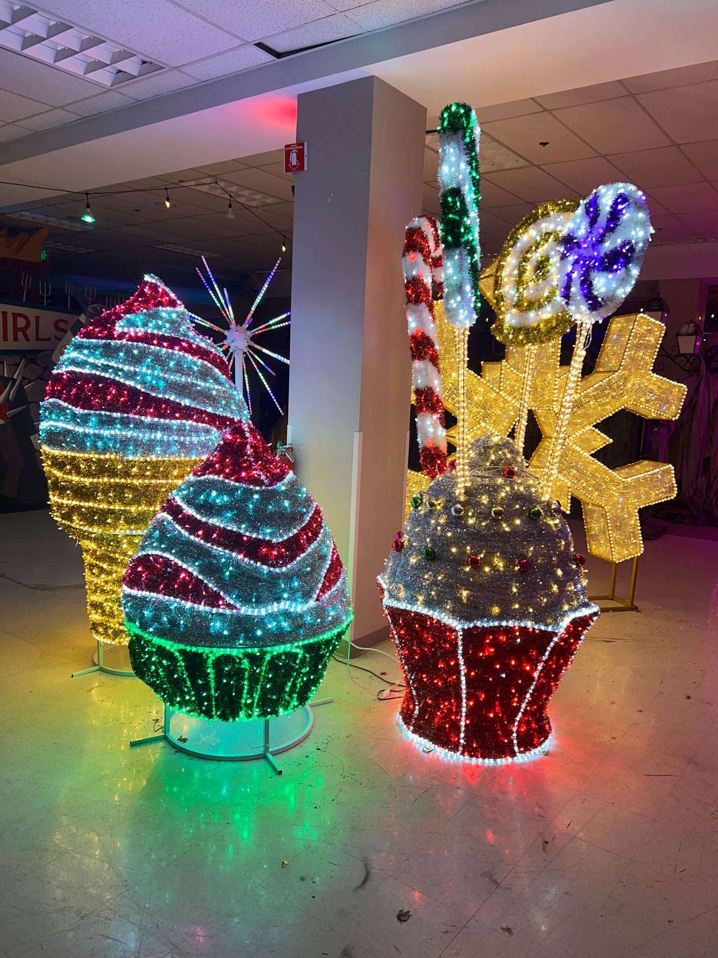 Indoor colorful holiday light decorations shaped like cupcakes, candy canes, lollipops, ice cream cone, and a snowflake.